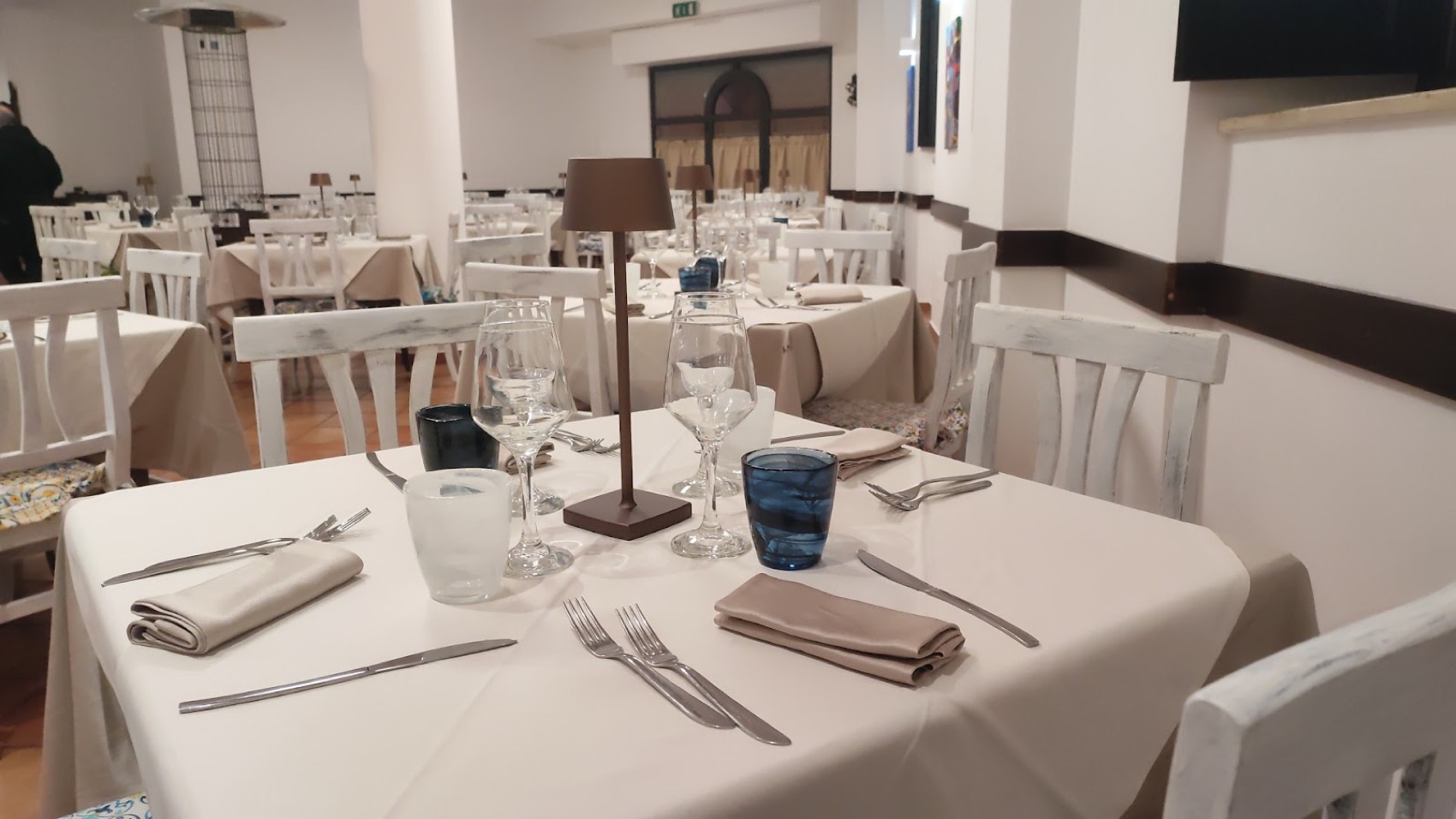 La sala del ristorante La Taverna, apparecchiata con tovaglie chiare